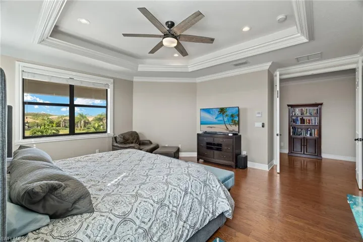 Enormous Bedroom Suite featuring ornamental molding, ceiling fan, dark hardwood / wood-style floors, and a tray ceiling