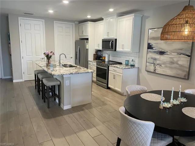 Kitchen featuring white cabinets, stainless steel appliances, sink, and light wood-type flooring