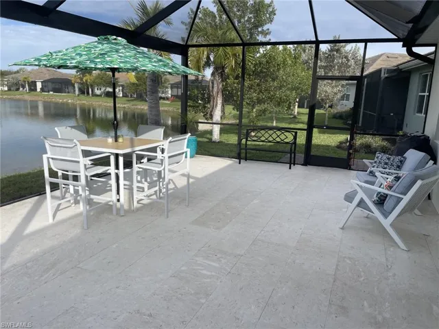 View of patio featuring a water view and glass enclosure