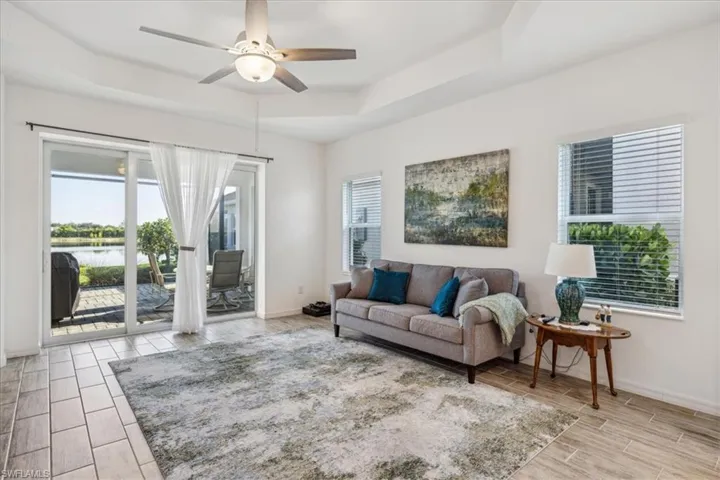 Living room featuring ceiling fan, light tile floors, and a raised ceiling