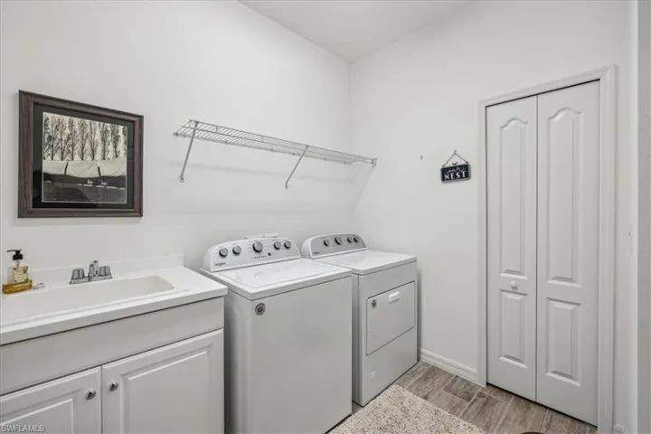 Laundry area featuring sink, light hardwood / wood-style floors, washer and clothes dryer, and cabinets