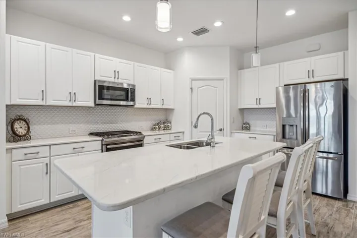 Kitchen with tasteful backsplash, decorative light fixtures, and appliances with stainless steel finishes