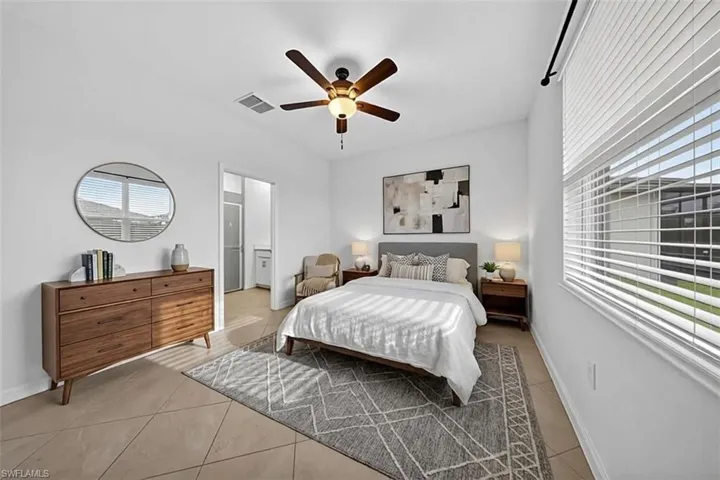 Bedroom featuring a ceiling fan, light tile patterned floors, and multiple windows