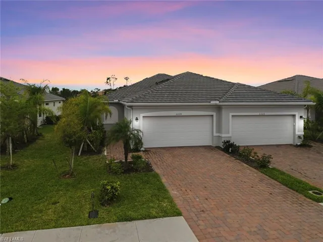Ranch-style house featuring stucco siding, decorative driveway, an attached garage, and a yard