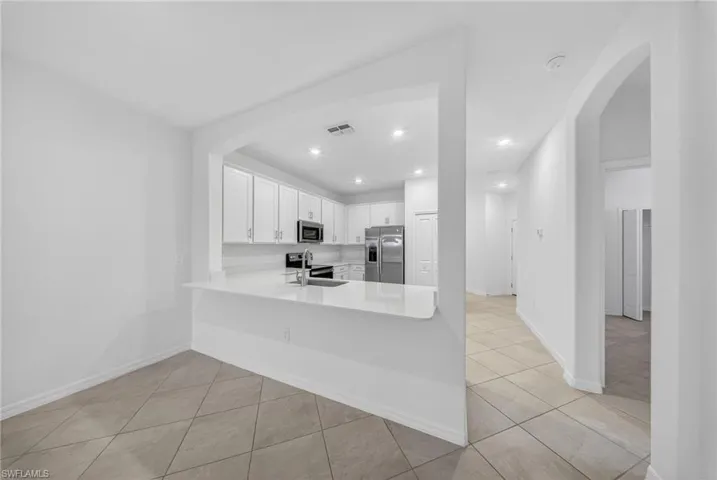 Kitchen with arched walkways, white cabinetry, stainless steel appliances, a peninsula, and recessed lighting