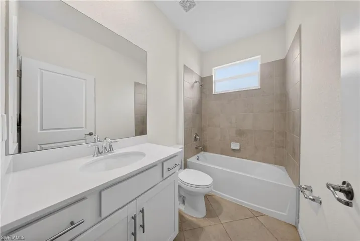 Bathroom featuring vanity, bathtub / shower combination, and light tile patterned flooring