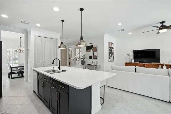 Kitchen featuring dishwasher, ornamental molding, dark cabinets, light countertops, and open floor plan
