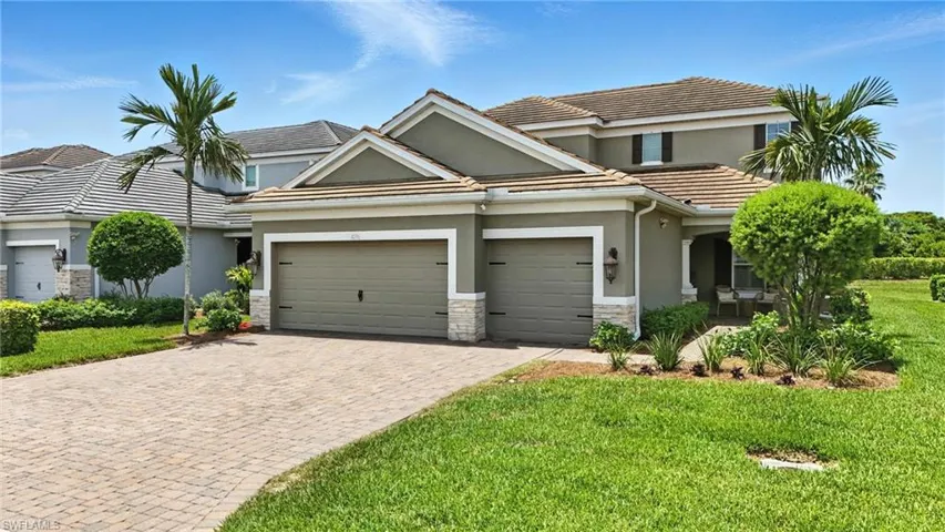 View of front facade featuring stucco siding, an attached garage, stone siding, driveway, and a front lawn