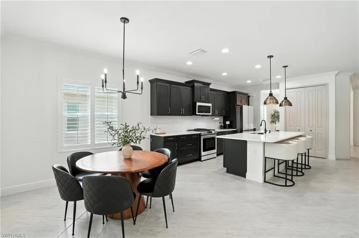 Dining area with ornamental molding, a chandelier, recessed lighting, and light tile patterned floors