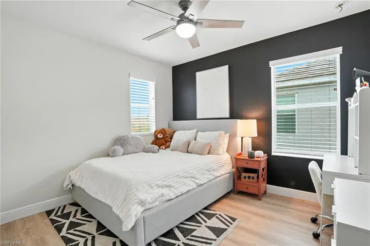 Bedroom with light wood-type flooring, ceiling fan, and an office area