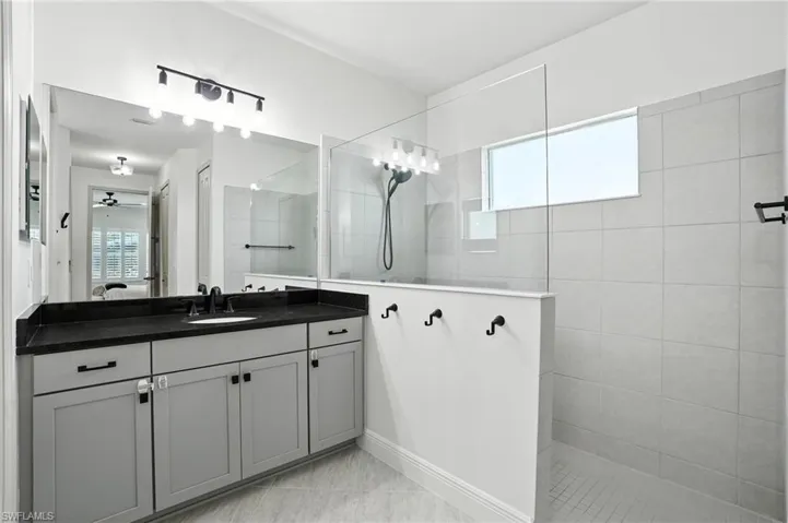 Ensuite bathroom featuring vanity, walk in shower, and a ceiling fan