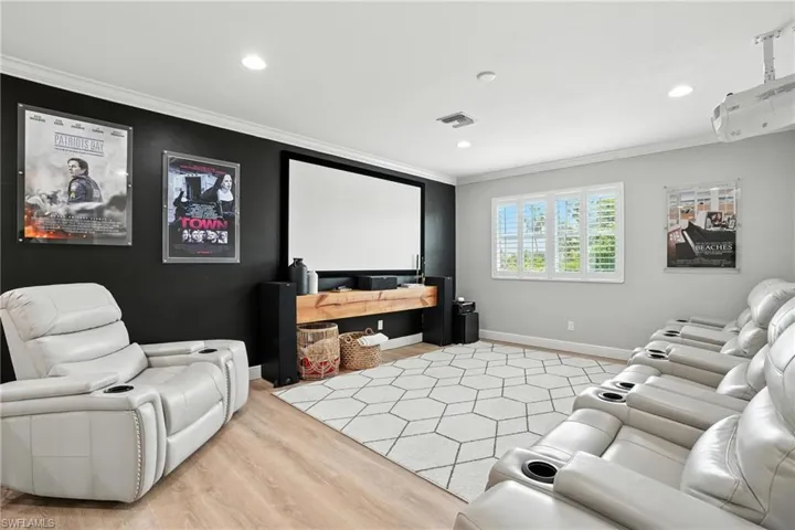Home theater featuring crown molding, recessed lighting, and light wood-style floors