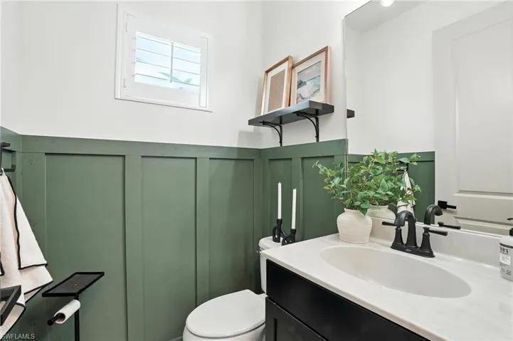 Bathroom featuring a decorative wall, vanity, and wainscoting