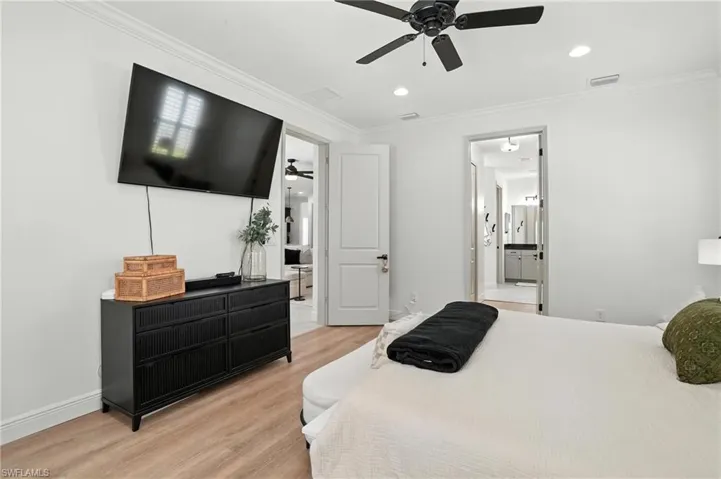 Bedroom with light wood-type flooring, ornamental molding, ensuite bath, recessed lighting, and ceiling fan