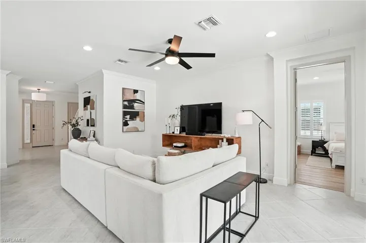Living area featuring a ceiling fan, recessed lighting, light tile patterned floors, and crown molding