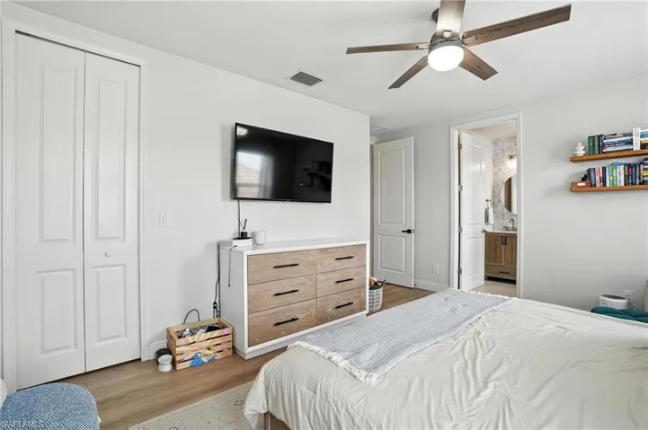 Bedroom with light wood-style flooring, a closet, a ceiling fan, and connected bathroom