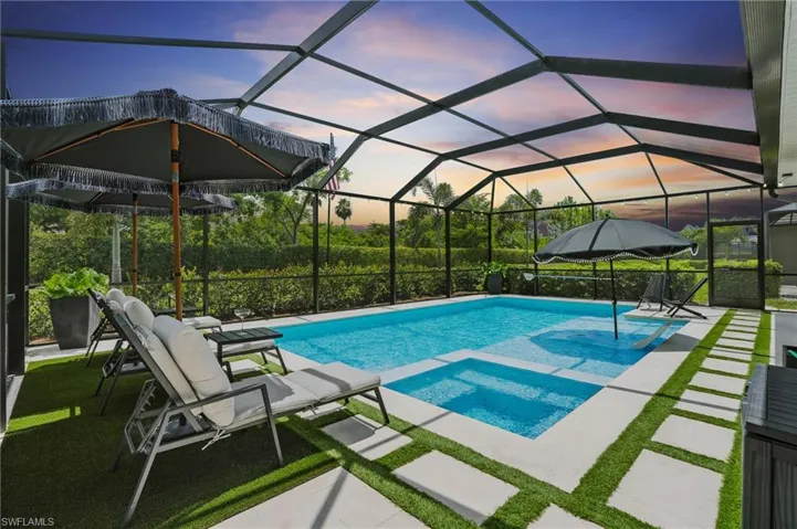 Pool at dusk featuring a patio area and a pool with connected hot tub