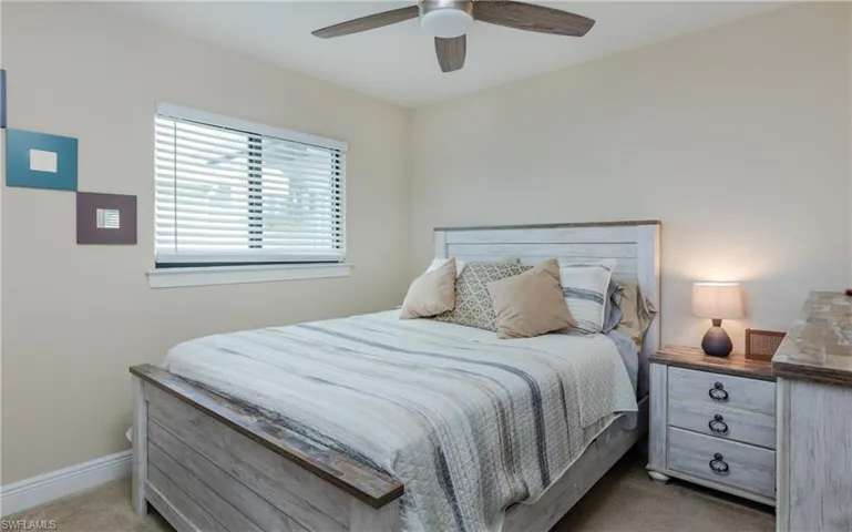 Bedroom with ceiling fan and light carpet