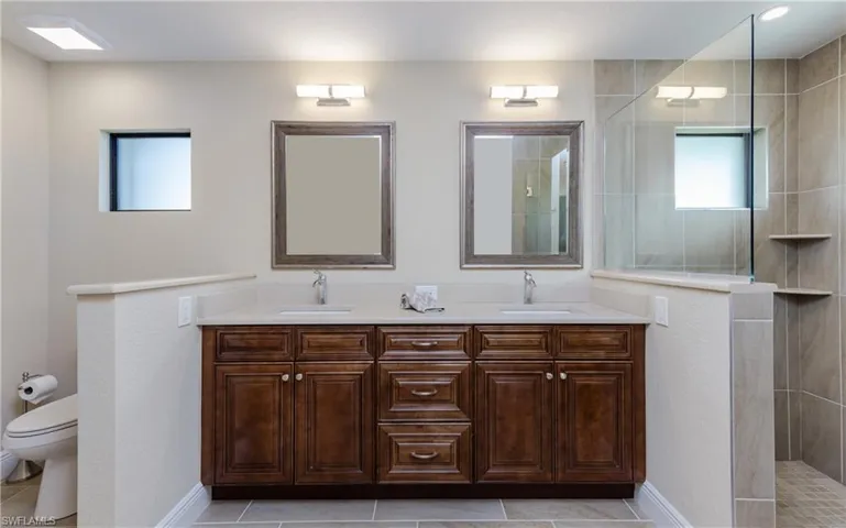 Bathroom with tile patterned flooring, a large walk-in tile shower, and double vanity