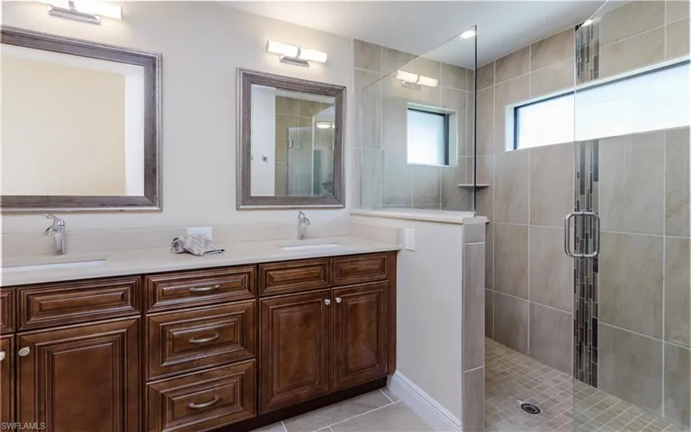 Bathroom with tile patterned floors, vanity, and walk in tile shower