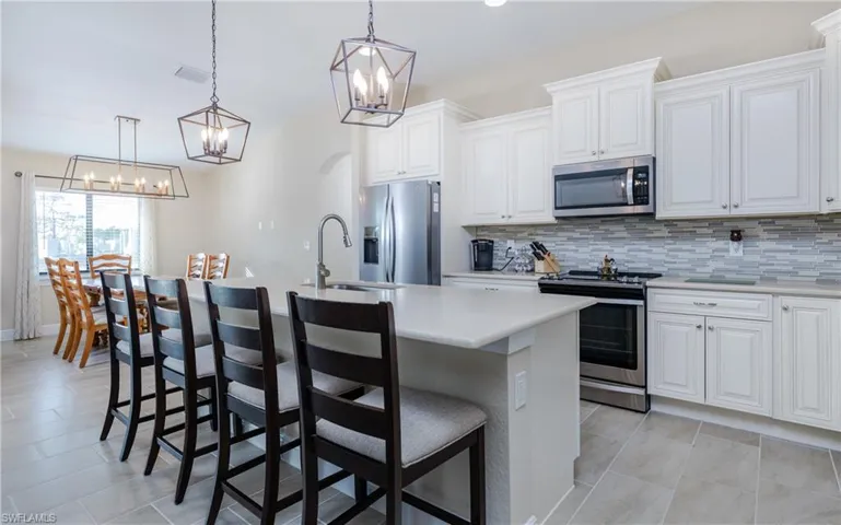 Kitchen with a center island with sink, white cabinets, stainless steel appliances, and tasteful backsplash