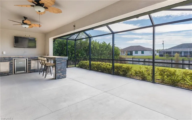 Large screened lanai featuring ceiling fan, sink, wine cooler, storage and a healthy amount of sunlight!