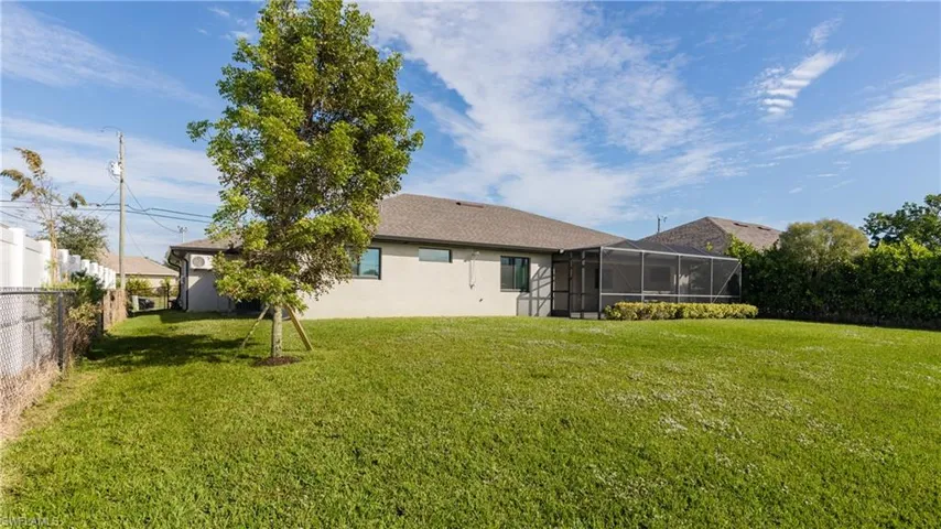 Rear view of property with manicured yard and lanai