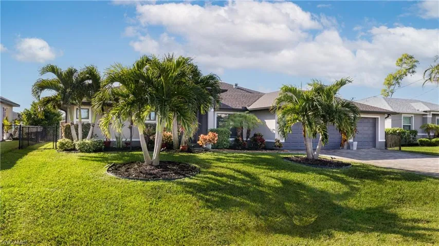 View of front of house featuring a 3-car garage and manicured lawn & mature landscaping