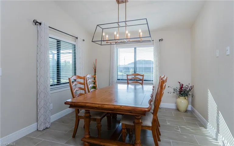 Tiled dining space with raised ceiling and a modern chandelier