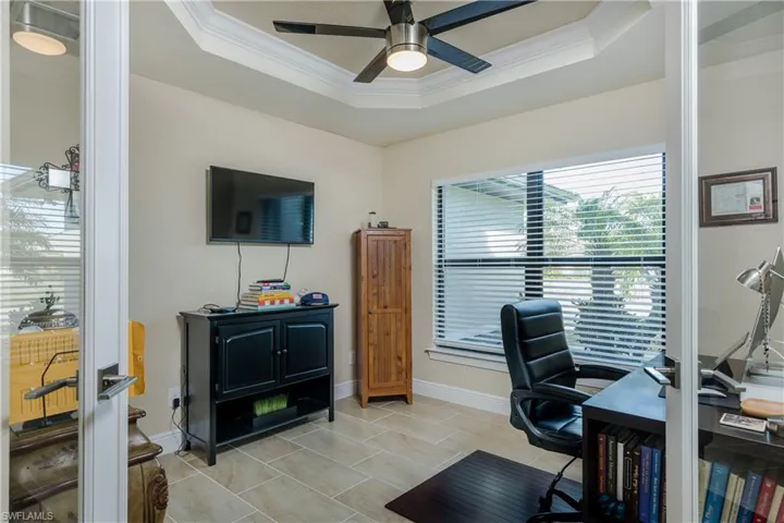 Office space featuring a tray ceiling, ceiling fan, and crown molding