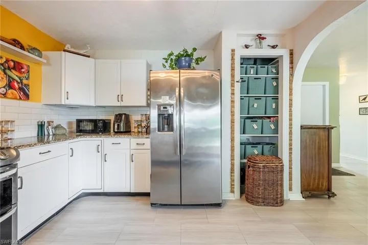 Kitchen featuring white cabinets, stainless steel appliances, tasteful backsplash, and stone counters