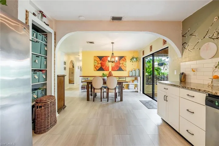 Kitchen with white cabinets, an inviting chandelier, light stone countertops, stainless steel appliances, and tasteful backsplash