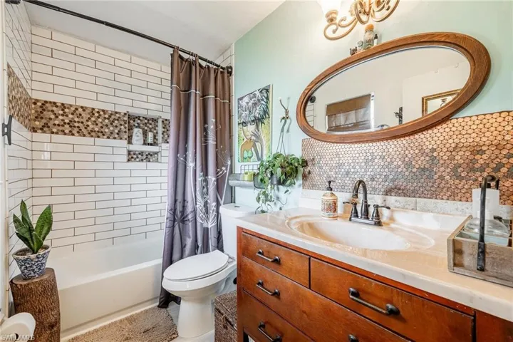 Full bathroom featuring vanity, toilet, decorative backsplash, and shower / bathtub combination with curtain