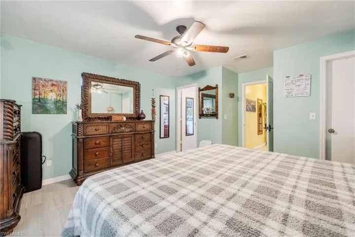 Bedroom with ceiling fan, ensuite bathroom, and light hardwood / wood-style flooring