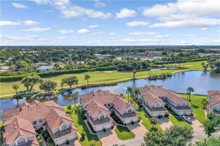 Aerial perspective of Spinnaker Pointe featuring clay tile roofing, paver driveways, and attached multi-car garages positioned along a water feature and green space