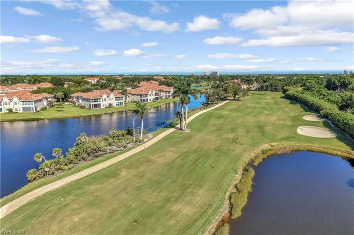 Aerial perspective of golf course grounds featuring expansive fairways, sand bunkers, multiple water features, and manicured landscaping with palm trees