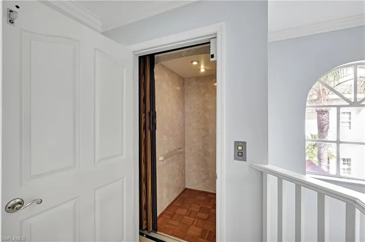 PRIVATE INTERIOR Residential elevator featuring wood parquet flooring, recessed lighting, and a sliding accordion door
