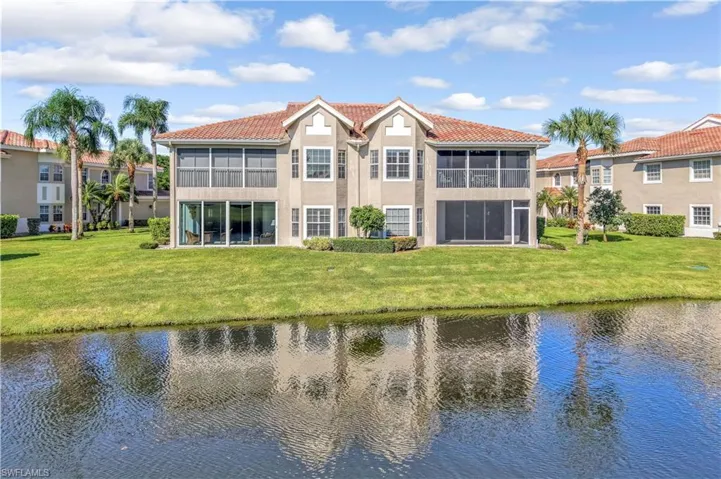 Two-story exterior featuring a tile roof, stucco finish, screened-in balconies, and ground-level patios overlooking a waterfront setting