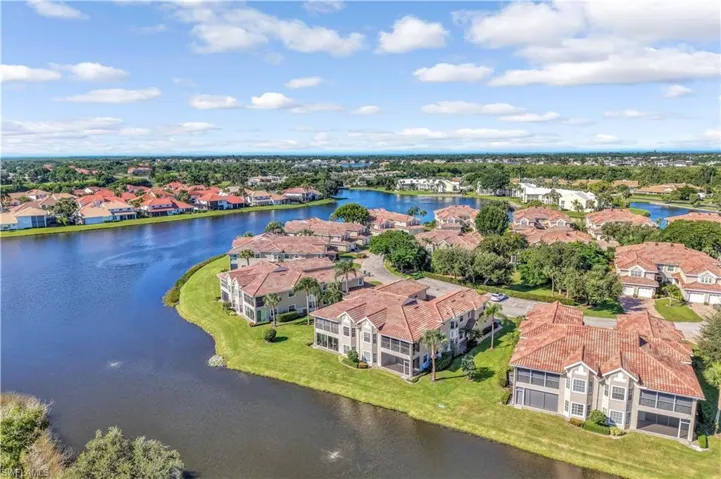 Waterfront community featuring multi-unit residences with terra cotta-style roof tiles, screened lanais, and manicured landscaping