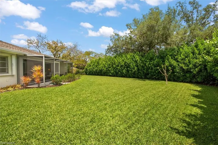Expansive green lawn with mature perimeter hedges and trees