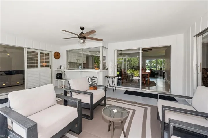 Covered patio featuring a ceiling fan with integrated lighting, white paneling, and sliding glass doors