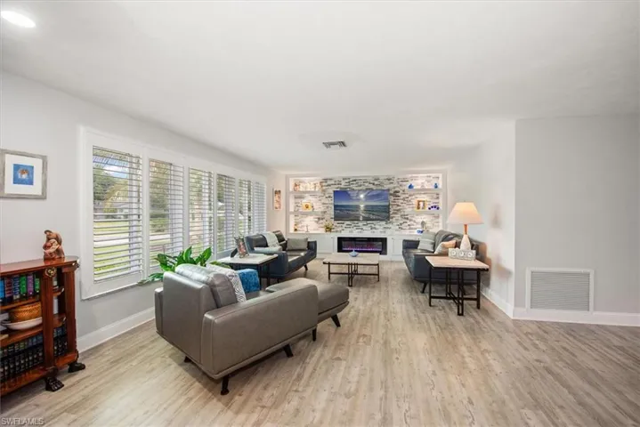 Open-concept living area featuring wood-finish flooring, a decorative stone accent wall with built-in shelving, and an integrated fireplace