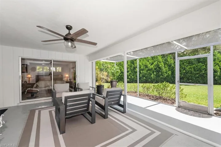 Screened patio with painted concrete flooring, ceiling fan, and sliding glass door entry