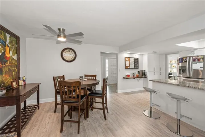 Open-concept living area featuring light wood-finish flooring, a modern ceiling fan, and white walls