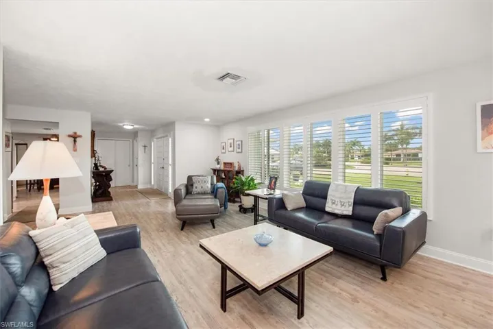 Bright living space featuring wood-finish flooring, white plantation shutters, and recessed lighting