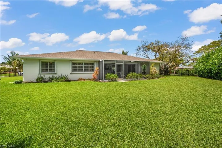 Expansive green lawn surrounds the property, featuring a light-colored exterior and a screened patio