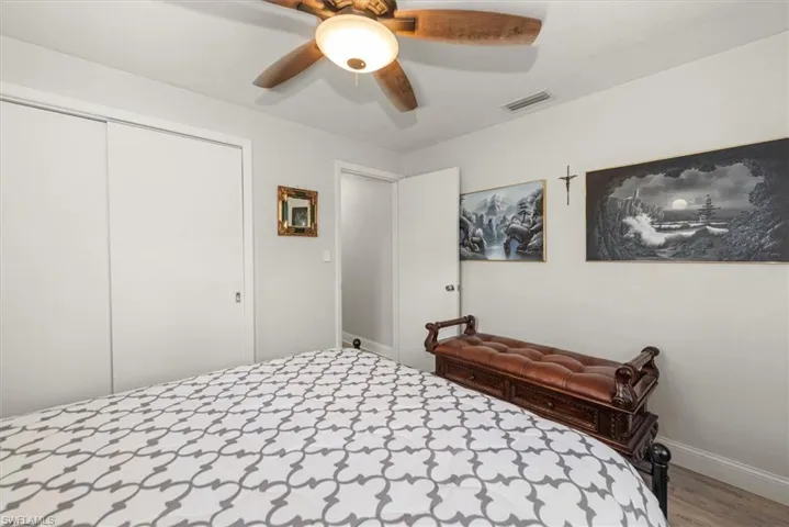 Bedroom with light gray walls, wood-finish ceiling fan, and sliding closet doors
