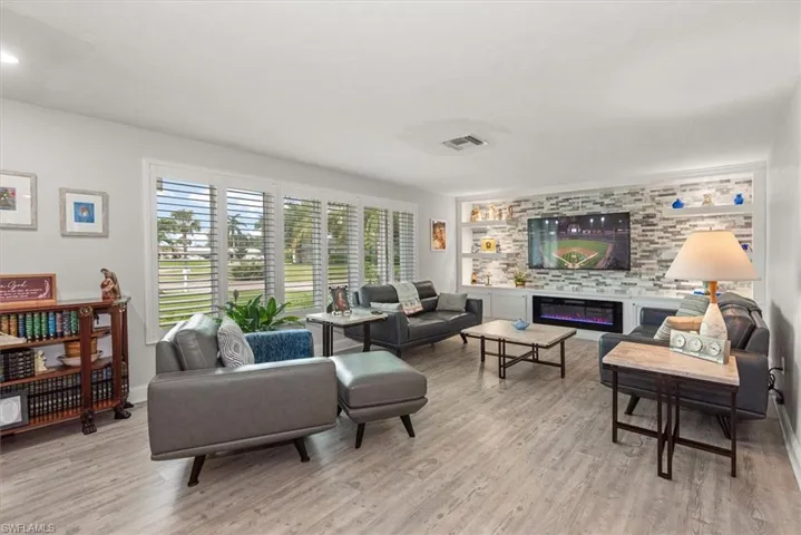 Spacious living area featuring wood-finish flooring, a built-in media console with stacked stone accent wall, and an electric fireplace