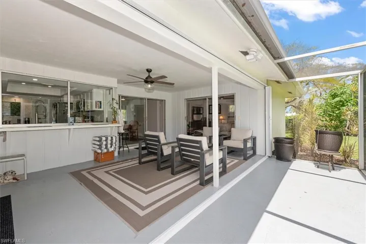 Screened patio featuring a ceiling fan, pass-through window to the interior, and sliding glass doors