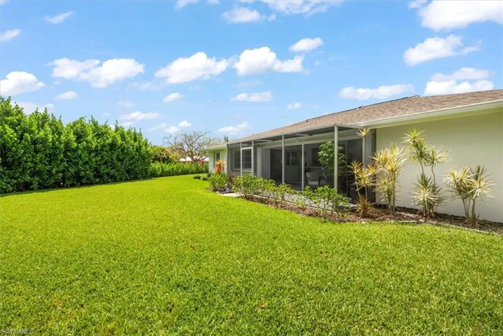 Expansive green lawn bordering a screened-in patio and stucco exterior